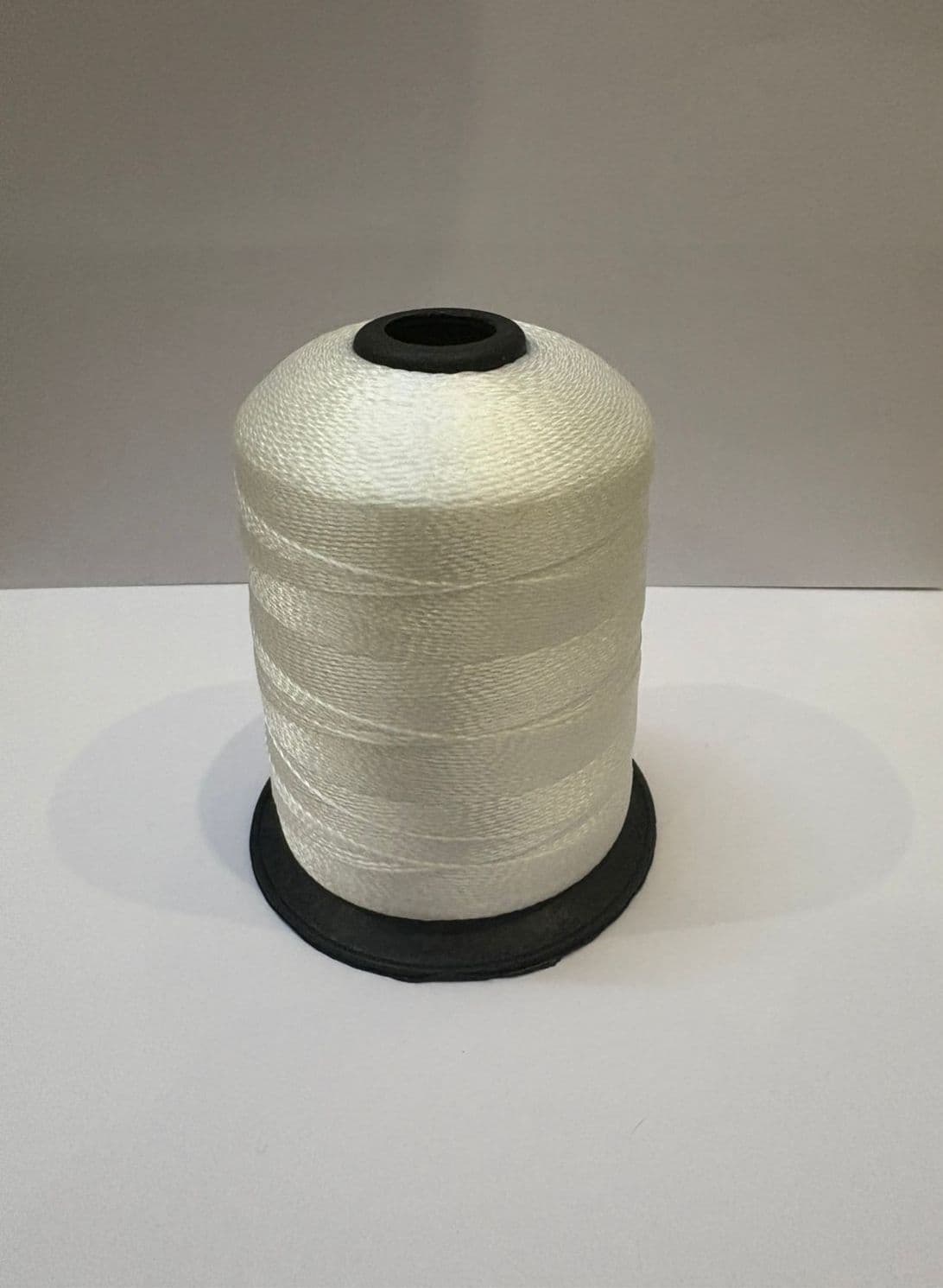 Polypropylene bag closing thread cone on white surface